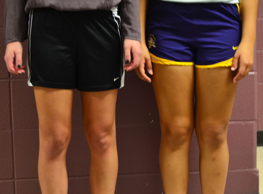 High school girls showing the acceptable(left) and unacceptable(right) lengths of track shorts.