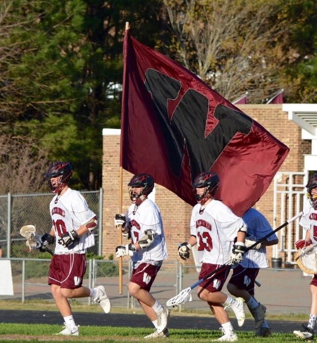 The lacrosse team runs onto the field before their game.