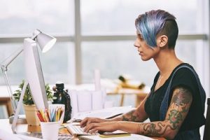 Women working at desk with tattoos and colored hair.