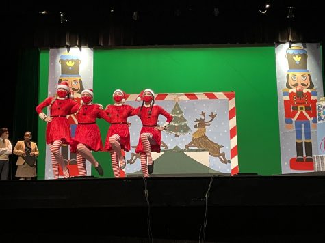 Four people perform on stage at a Christmas themed play. 