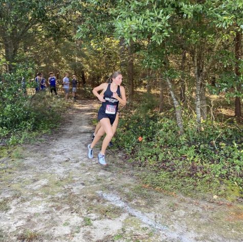 Athletic cross-country member runs on course during meet.