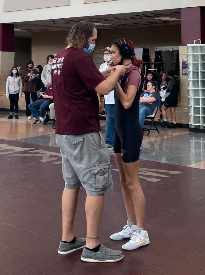 Coach Williams helps Junior Samantha Child secure her headgear for her first tournament.