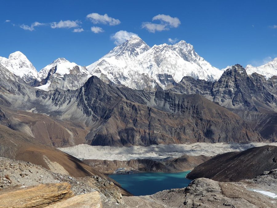 A lake sits still in front of Mount Everest. Mount Everest is the tallest mountain in the world.