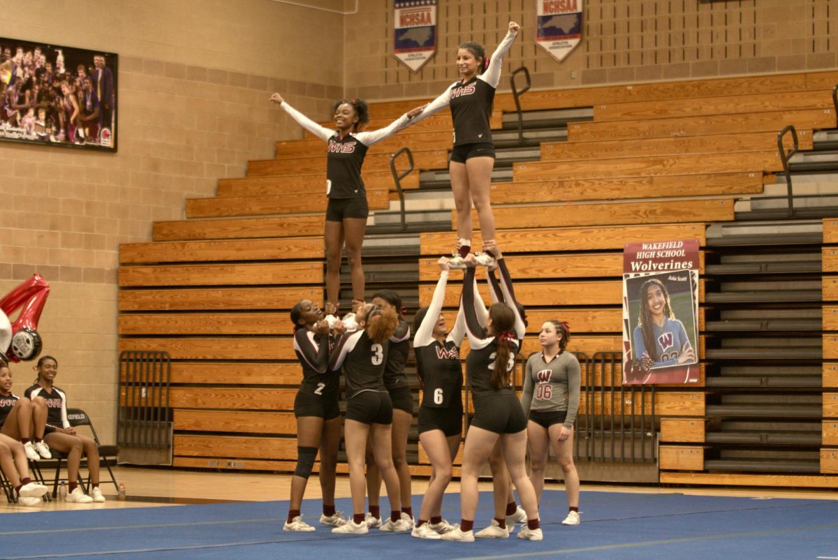 The flyers of the stunt team pose as they are lifted off the ground by their strong bases.