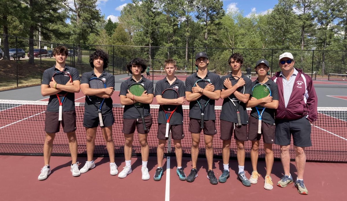 The players of Wakefield’s tennis team pose for a photo holding their racquets with Coach Ken Stewart.